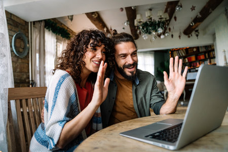 Young smiling couple having online family video call at homeの写真素材