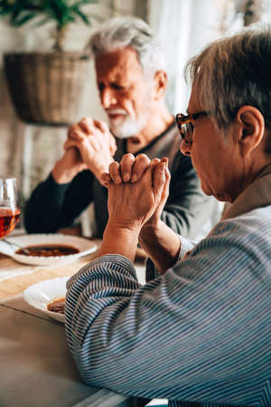 Christian senior couple praying at table worshipping the Lordの写真素材