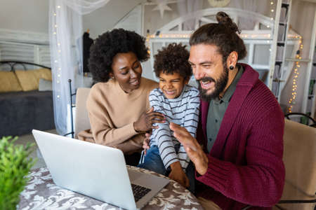 Young multiethnic cheerful family talking through video chat with relativesの写真素材