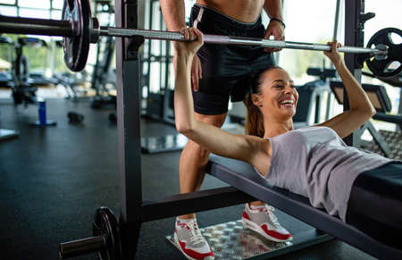 Personal trainer helping woman to working out in gym. Healthy lifestyle sport people conceptの写真素材