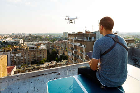 Young technician flying UAV drone with remote control on rooftopの写真素材