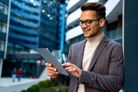 Happy young business man with tablet at work in modern urban backgroundの写真素材