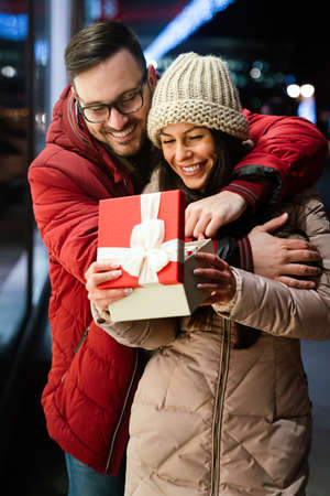 Beautiful couple in love is celebrating with gift outdoor. Enjoying time together in Valentinesの写真素材