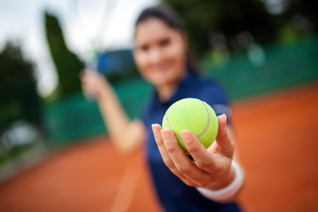 Young handsome tennis player with racket and ball prepares to serve at beginning of game or match.の写真素材