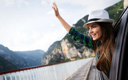 Woman in car road trip waving out the window smilingの写真素材