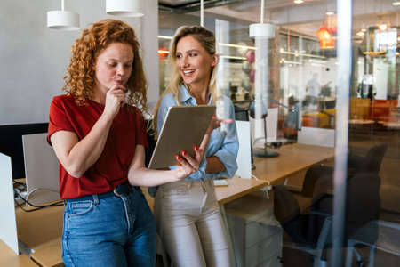 Portrait of happy business people having fun and using digital tablet at workplace officeの写真素材