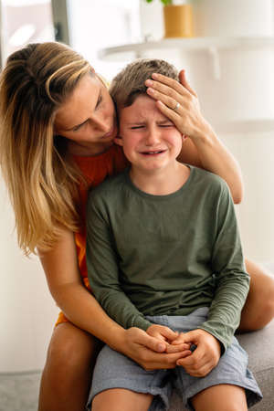 Portrait of mother consoling her crying sad injured son. Child family support parent conceptの写真素材