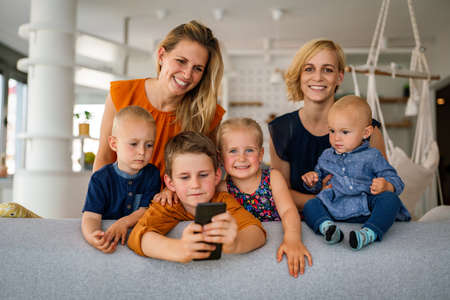 Portrait of happy big family. Gay couple of women smiling and having fun with children at home