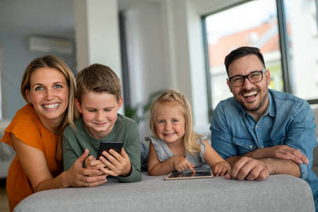 Happy young family having fun time at home. Parents with children using tablet