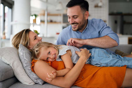 Parents having fun with their little daughter on bed. Family spending time at the morning.の写真素材