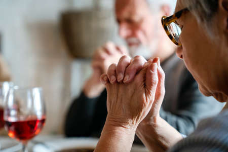 Christian senior couple praying at table worshipping the Lordの写真素材