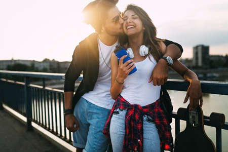 Portrait of happy couple having fun while driving a long board in city. People skateboard concept