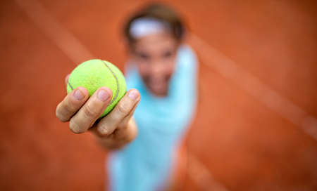 Young handsome tennis player with racket and ball prepares to serve at beginning of game or match.の素材 [FY310182086915]