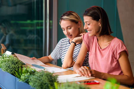 Portrait of two beautiful women having fun together and chatting in cafeの写真素材
