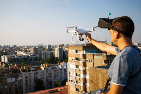 Young technician man flying UAV drone with remote control in city
