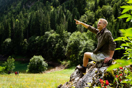 Handsome happy backpacker man hiking, camping through mountain forest.の写真素材