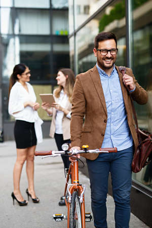 Portrait of happy fit business man with bicycle in modern city outdoors.の写真素材