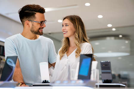 Tech shopping device gadget concept. Happy young people buying a new smartphone in mobile shop.の写真素材