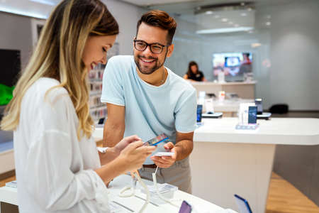 Shopping a new digital device. Happy couple buying a smartphone in store.
