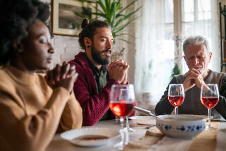 Multiethnic family praying at the table worshipping the Lord