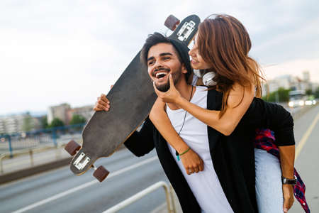 Portrait of young couple with skateboard and longboard having fun outdoorsの写真素材