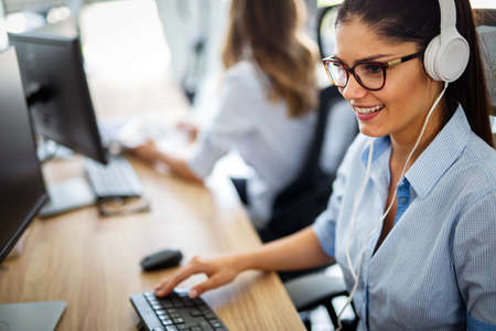 Smiling friendly female call-center agent with headset working on support hotline in the office