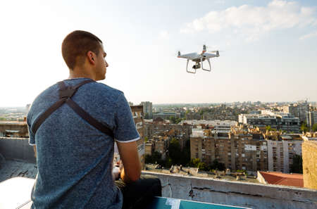 Man operating a drone with remote control on rooftop
