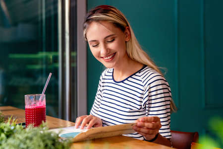 Young woman having a good morning healthy smoothie drink made of super foods. People health concept