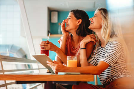 Portrait of happy women friends spending fun time together with digital devices