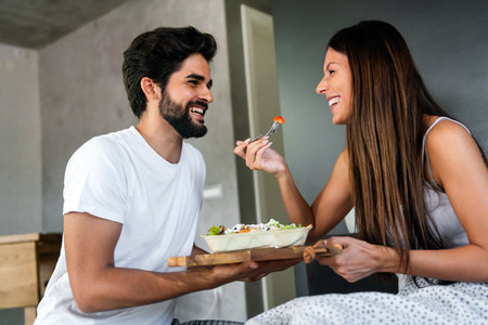 Young romantic man brings breakfast to woman in the bed and laughing together after wakes up.の写真素材