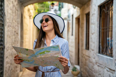 Cheerful woman with trendy look searching direction on location map while traveling abroad in summer