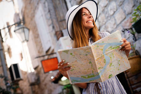 Young female tourist with map looking for a way on summer vacation
