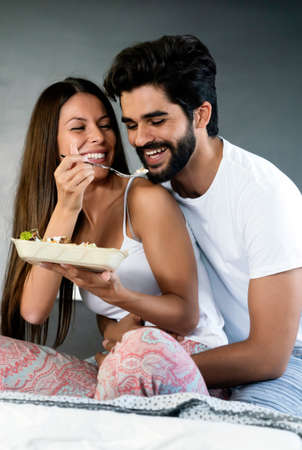 Healthy breakfast in bed. Young beautiful couple in love is sitting on bed and having breakfast.の写真素材