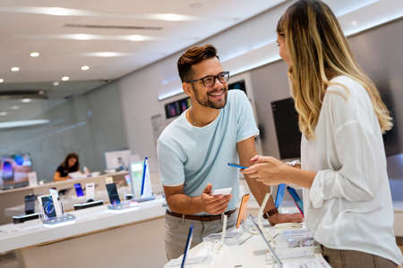 Tech shopping device gadget concept. Happy young people buying a new smartphone in mobile shop.