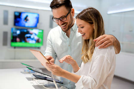 Shopping a new digital device. Happy young couple buying a tablet PC in store.の写真素材