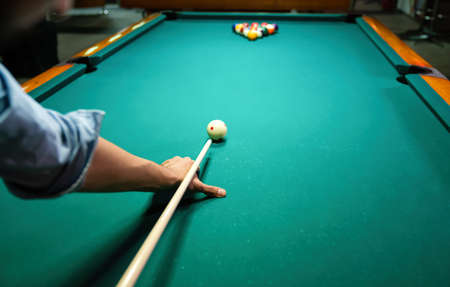 Preparing to break spheres into the pool pocket. People billiard, snooker entertainment concept.