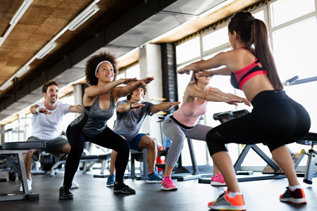 Multiethnic group of people training in a gym. Trainer and sportive fit persons exercising