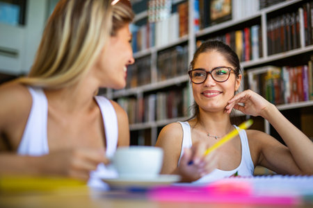 Happy young university students studying with books in library.の写真素材