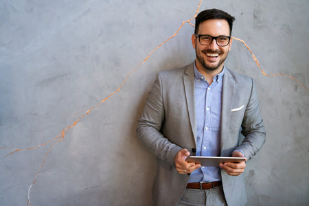 Portrait of young successful businessman with digital device working in corporate business officeの写真素材