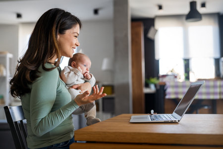 Family technology motherhood concept. Happy smiling young mother with baby. Video communicationの写真素材