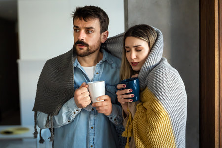 Freezing man and woman suffering from cold or flu fever or having trouble with central heatingの写真素材