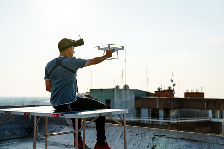 Young technician flying UAV drone with remote control on rooftopの写真素材