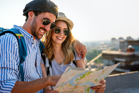Happy tourists couple, friends sightseeing city with map together. Travel people concept.の写真素材