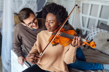 Private male music teacher giving violin lessons to a woman at home. Couple love romance concept.の写真素材