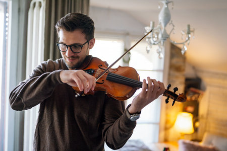 Young caucasian man playing violin at home. Hobby quality time happiness concept.