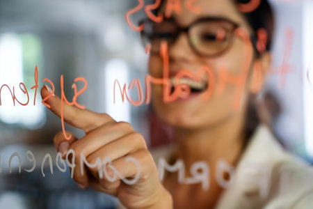 Female coach making notes of information during workflow planning strategy for startup projectの写真素材