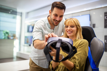 Young happy couple playing video games with virtual reality glasses in technical store