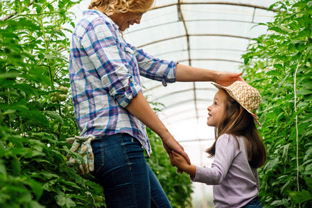 Agriculture, farm and mother with girl in greenhouse garden to check growth of plants.の写真素材