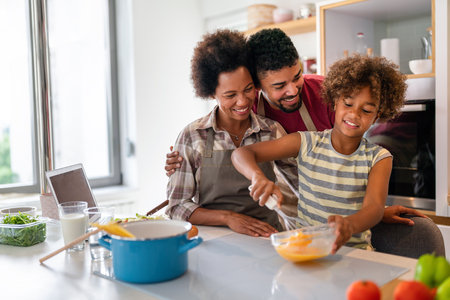 Happy african american family preparing healthy food in kitchen, having fun together on weekendの写真素材