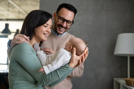 Portrait of young happy man and woman holding newborn cute baby. Happy family conceptの写真素材